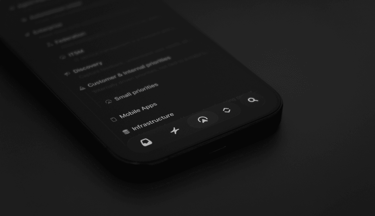 Close-up of a smartphone showing the Linear app interface, with a blurred list of projects and navigation icons along the bottom.